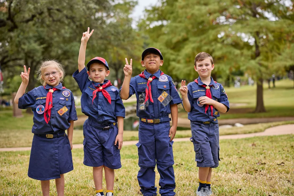 Four Cub Scouts in uniform giving the Scout sign